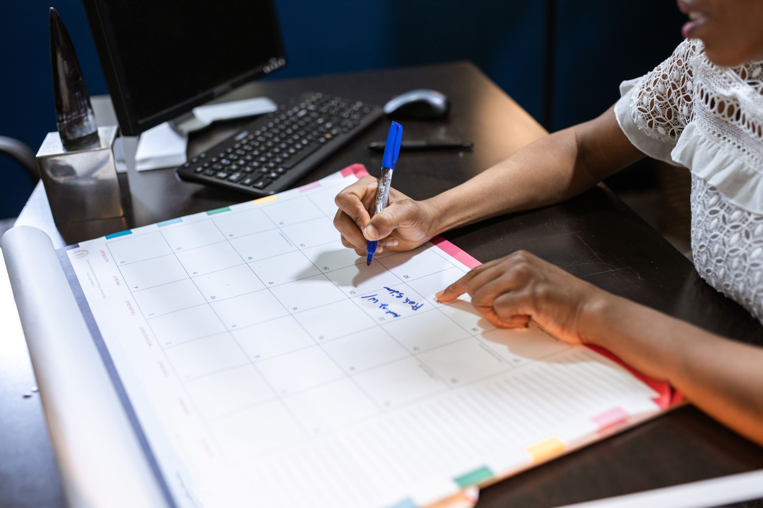 Personne écrivant dans un calendrier de bureau
