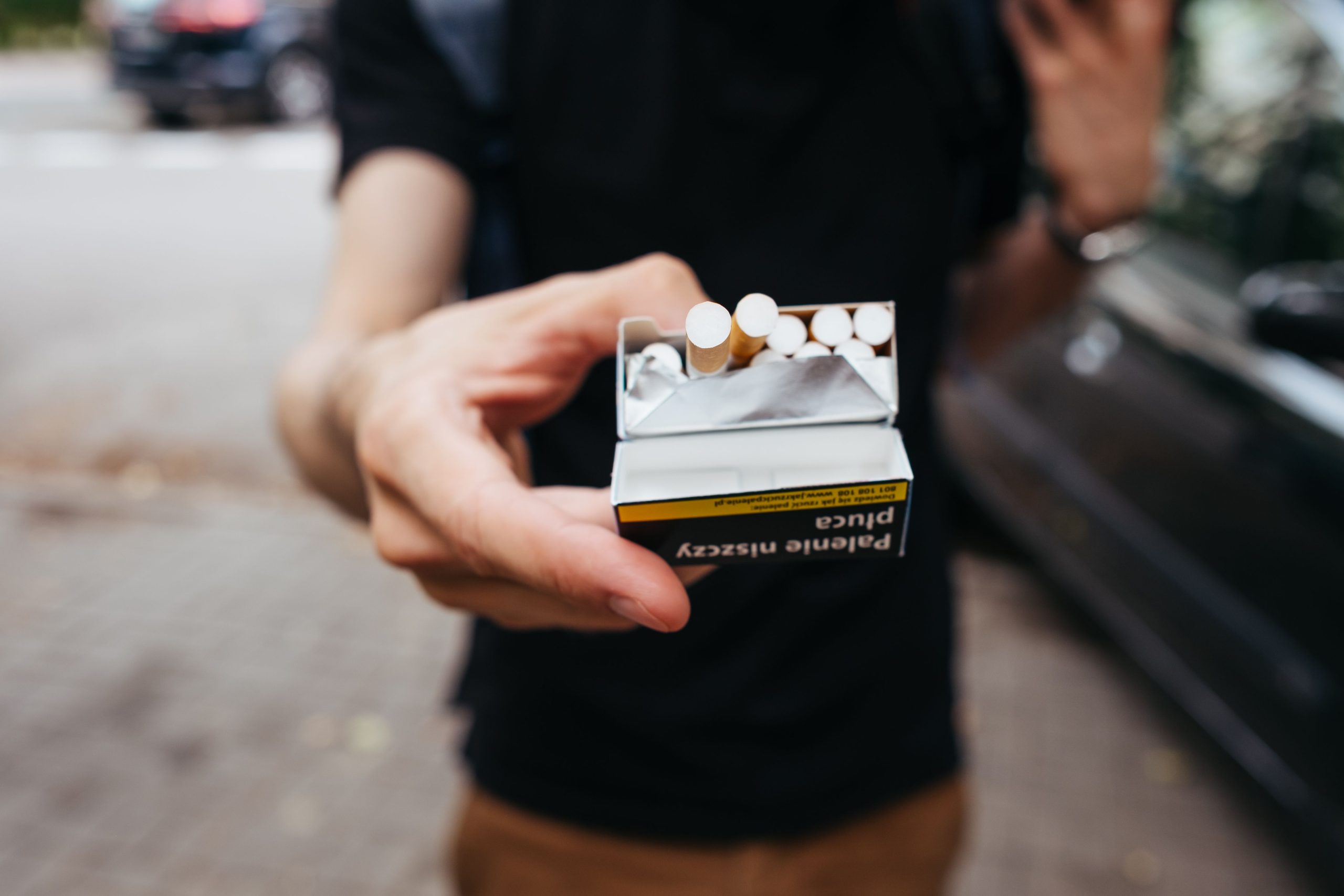 Homme offrant un paquet de cigarettes en rue