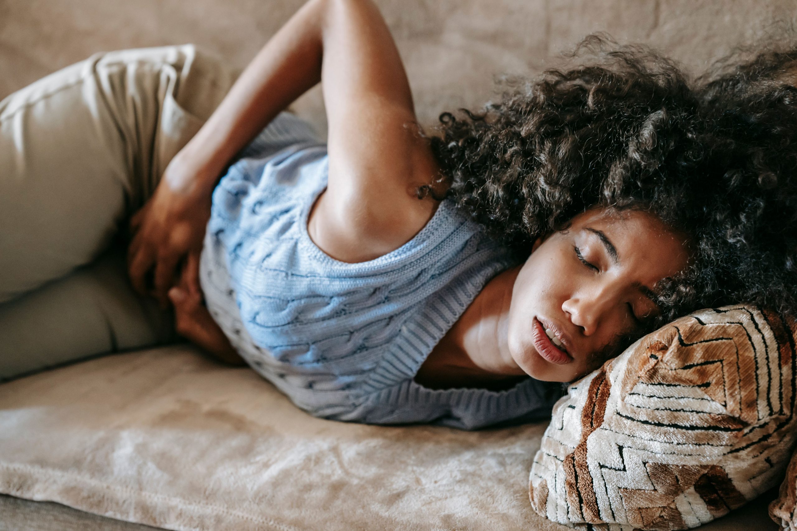 Femme souffrant de mal de ventre sur le canapé