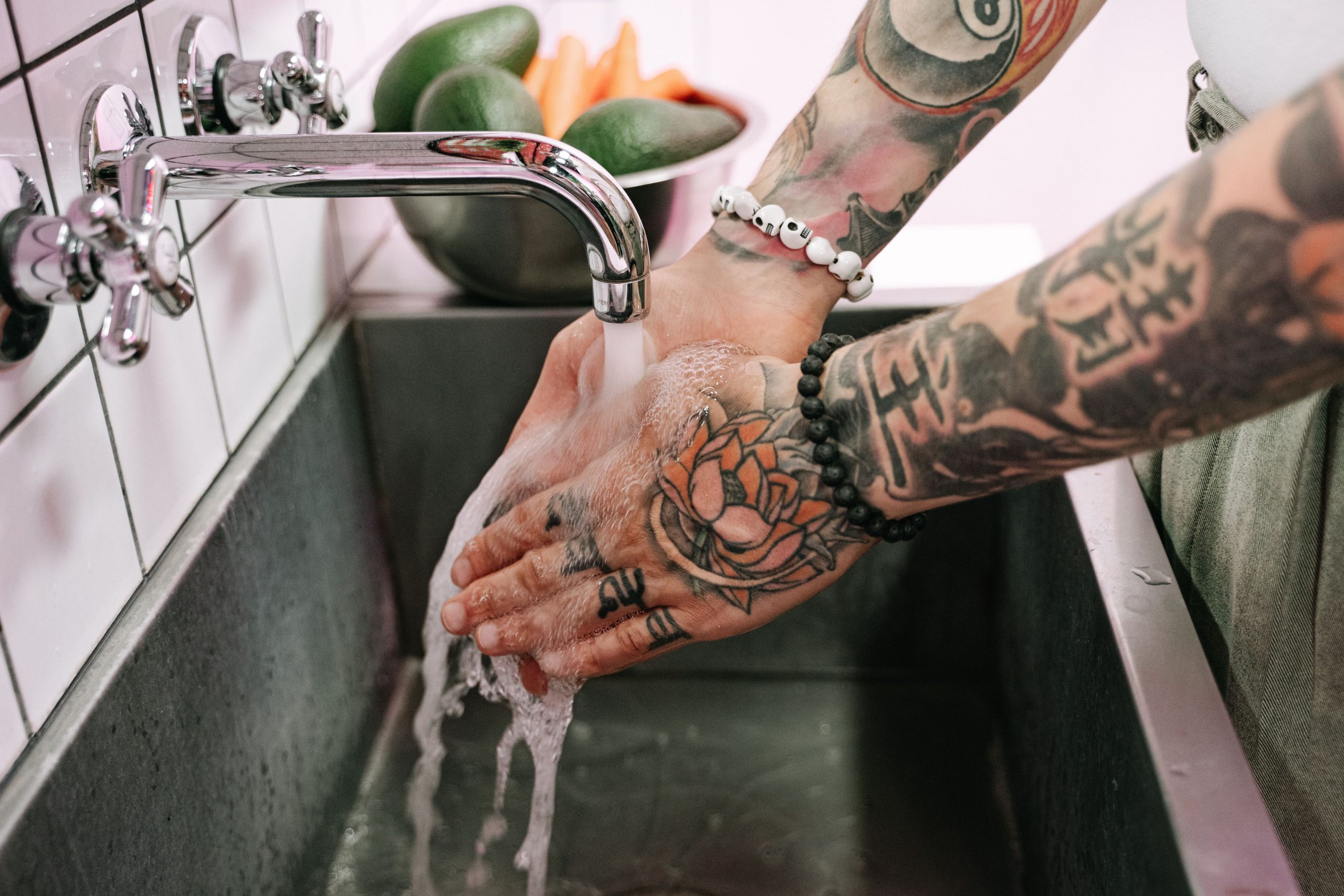 Mains tatouées se lavant près de légumes frais