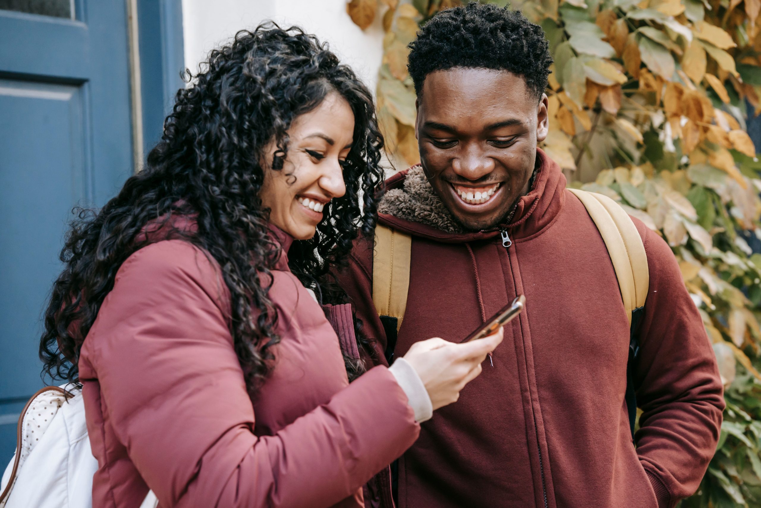 Couple heureux souriant avec telephone mobile dehors