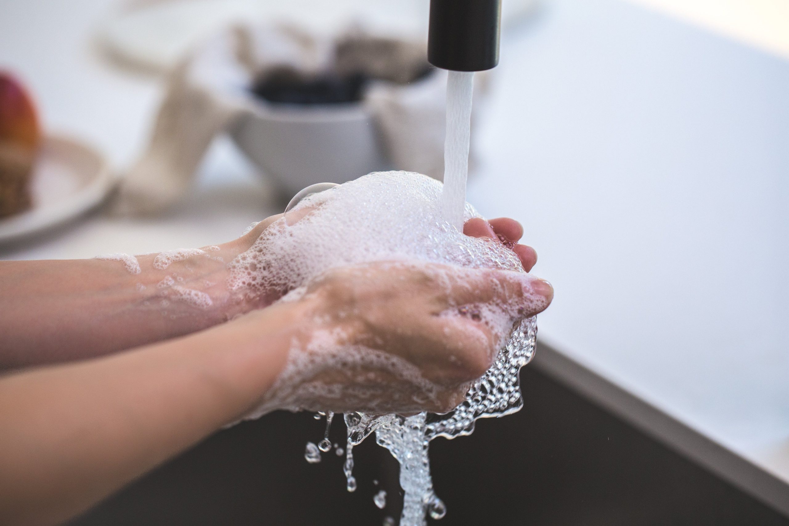 Mains lavées avec du savon mousseux sous robinet