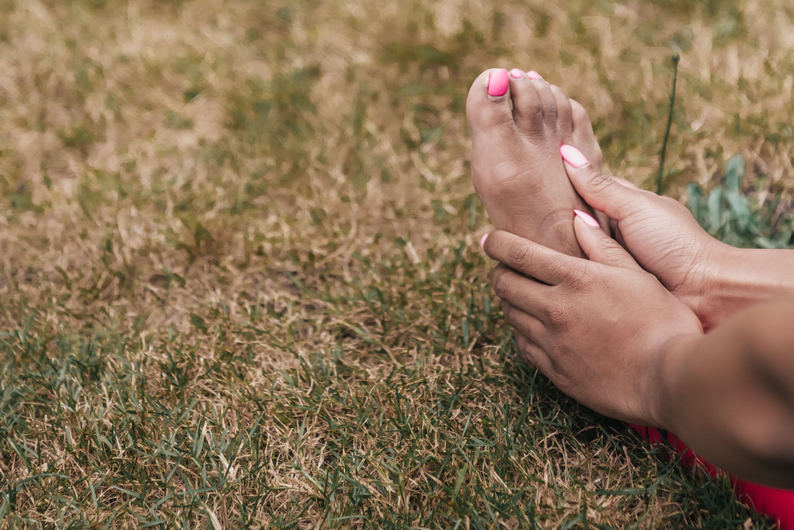 Mains tenant délicatement un pied sur herbe verte
