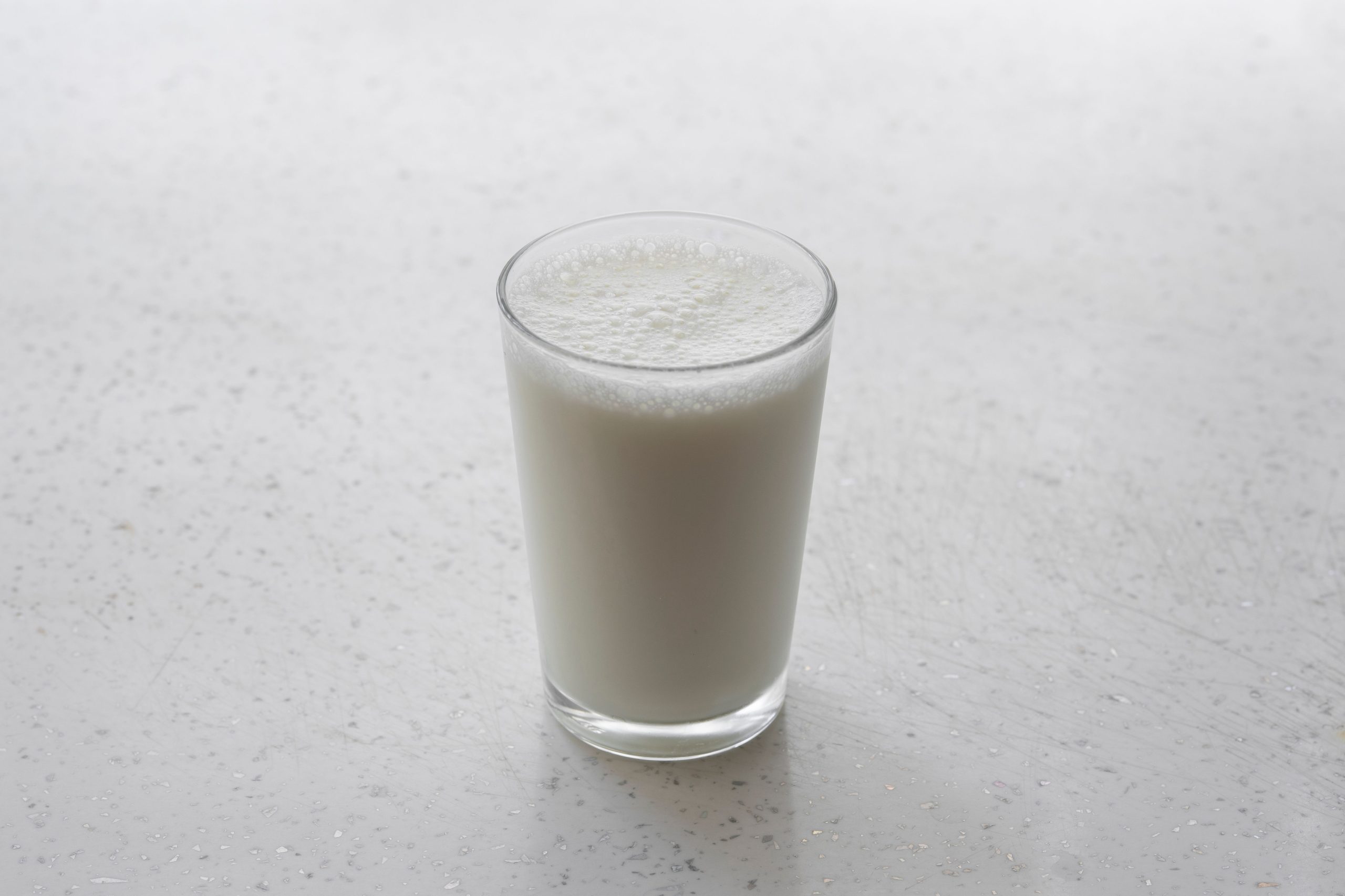 Verre de lait mousseux sur surface blanche minimaliste